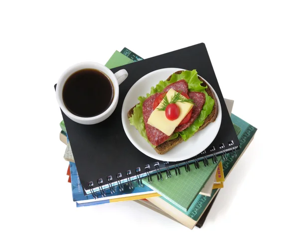 Een stapel boeken en notebooks met een kopje koffie en een sandwi — Stockfoto