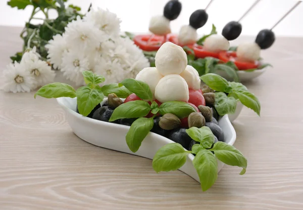 Appetizer of mozzarella, cherry tomatoes and olives and basil — Stock Photo, Image