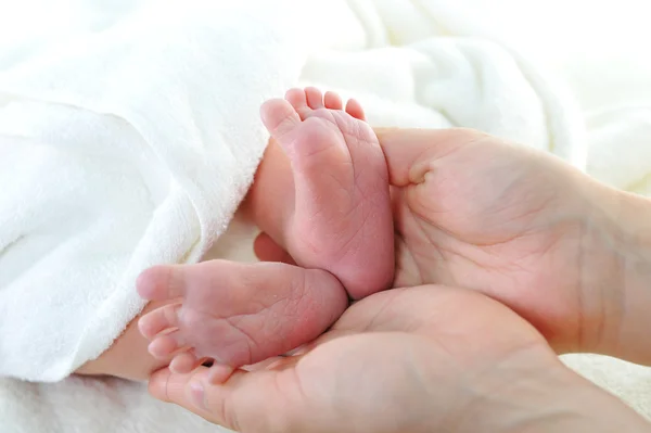 Pequeno pé de bebê nas mãos das mães — Fotografia de Stock