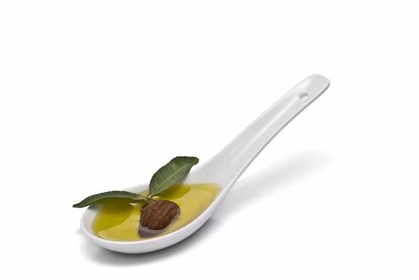 Spoon with oil and one almond. — Stock Photo, Image