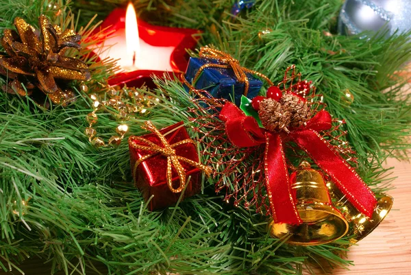 Bonita corona de Navidad verde, campanas doradas con cinta roja y vela roja —  Fotos de Stock