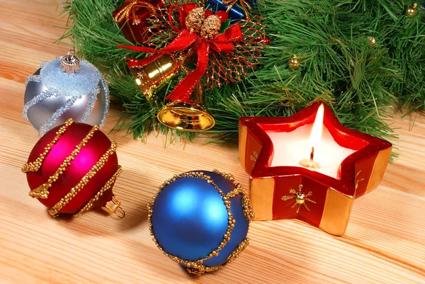 Bonitas decoraciones de Navidad: esferas rojas, plateadas y azules, campanas doradas, velas rojas y corona de Navidad sobre escritorio de madera —  Fotos de Stock