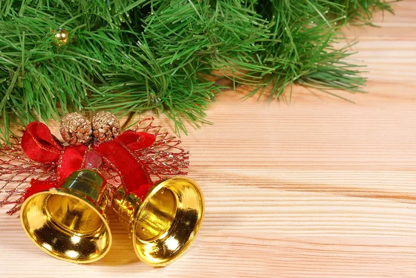 Bonitas campanas doradas con cinta roja y brunch de árbol de Navidad verde sobre escritorio de madera —  Fotos de Stock