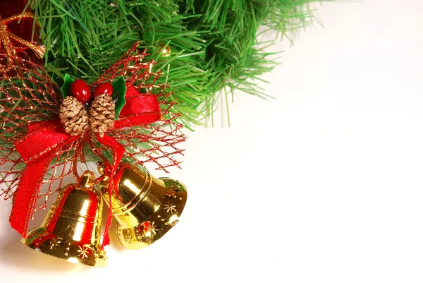 Schöne goldene Glöckchen mit rotem Band und grünem Weihnachtsbaum-Brunch über weißem — Stockfoto