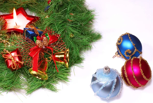 Pěkné vánoční ozdoby: červená, stříbrná a modrá koule, zlaté zvonky, červené svíčky a vánoční věnec nad bílá — Stock fotografie