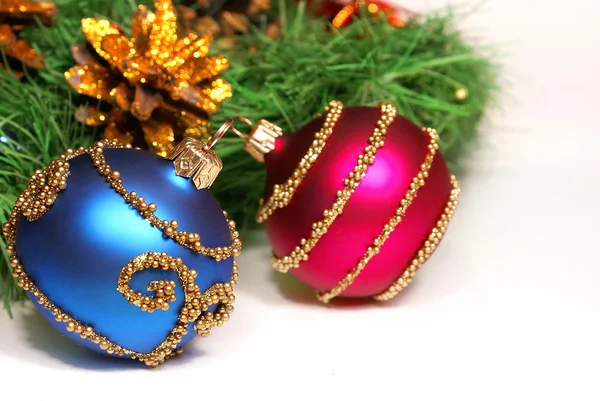 Nice Xmas decorations (red and blue spheres, golden cone and Xmas tree brunch) over white — Stock Photo, Image