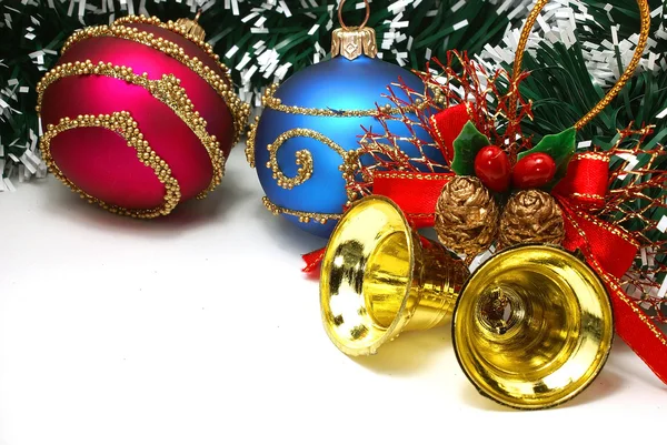 Красивые рождественские украшения: красные и синие шары, золотые колокола и гирлянда над белым — стоковое фото