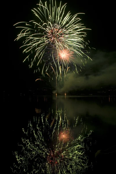 Colorful fireworks on black sky background with water reflection — Stock Photo, Image