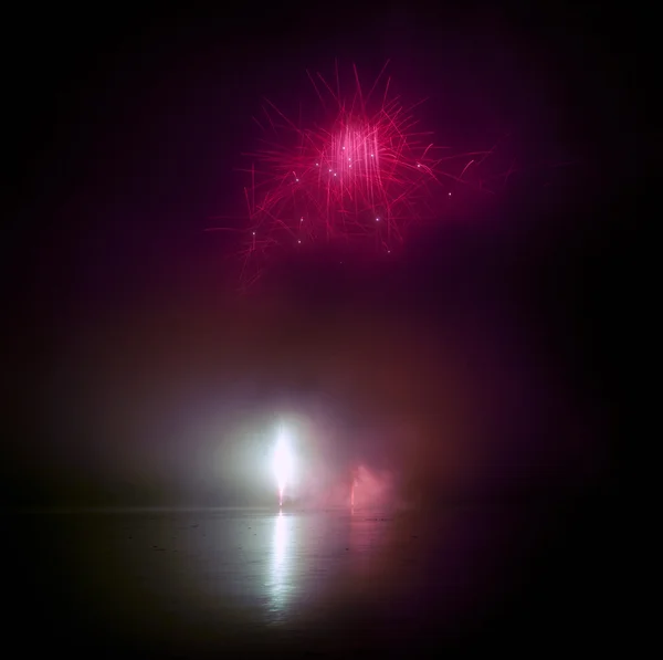 Coloridos fuegos artificiales en el fondo del cielo negro y el agua reflejan — Foto de Stock