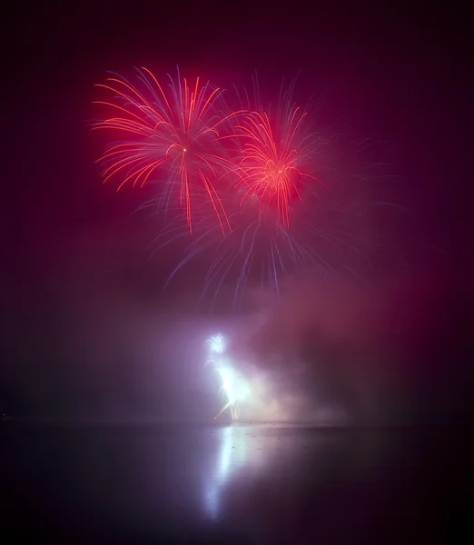 Coloridos fuegos artificiales en el fondo del cielo negro y el agua reflejan —  Fotos de Stock
