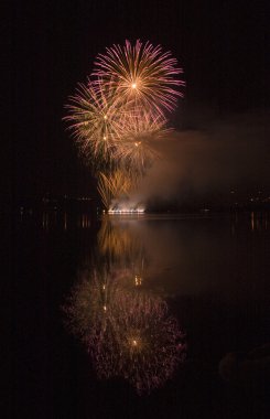 Colorful fireworks on black sky background with water reflection clipart