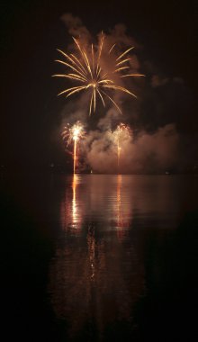 Colorful fireworks on black sky background with water reflection clipart