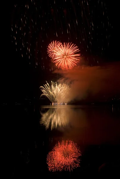 Colorful fireworks on black sky background with water reflection — Stock Photo, Image