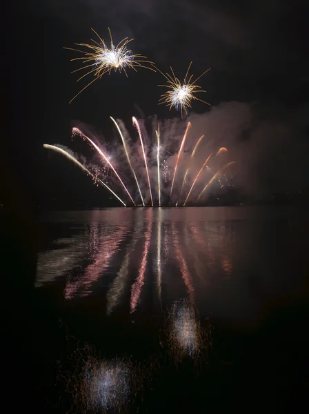 Színes tűzijáték a fekete ég háttere a víz tükrözi — Stock Fotó