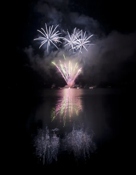 Buntes Feuerwerk auf schwarzem Himmel Hintergrund mit Wasserreflexion — Stockfoto
