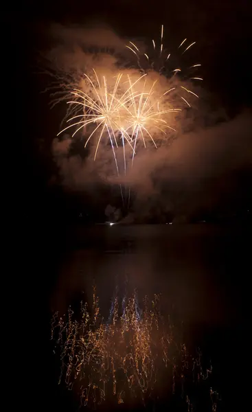 Színes tűzijáték a fekete ég háttere a víz tükrözi — Stock Fotó