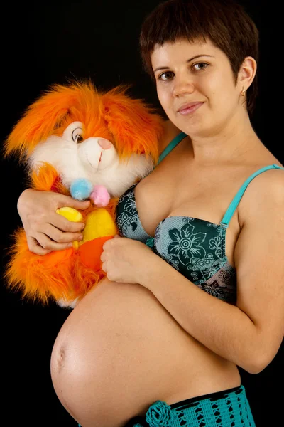 Vakker, gravid kvinne med et leketøy – stockfoto
