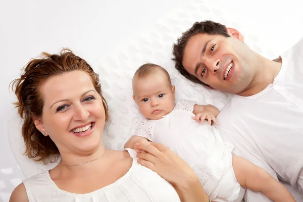 Happy young family lying in bed — Stock Photo, Image