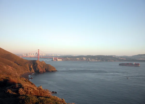 Barco de carga se dirige hacia el puente Golden Gate al anochecer — Foto de Stock