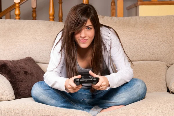 玩视频游戏集中在家里的沙发上的年轻女性 — 图库照片