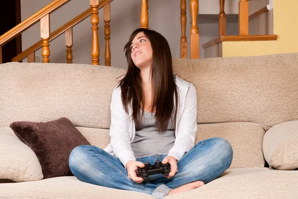 stock image Young female lose playing video-games concentrating on sofa at home