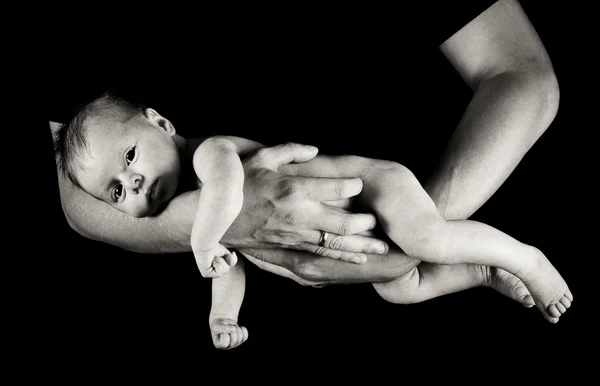 Bebé niña en padres brazos aislados en negro —  Fotos de Stock