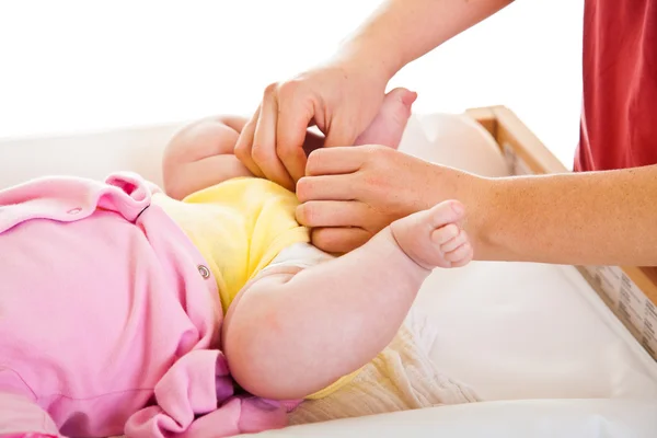 Mutter wechselt Windel für kleines Mädchen auf Kinderzimmertisch — Stockfoto