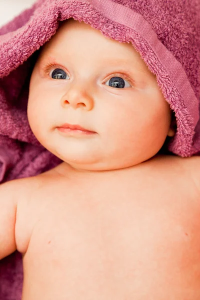 Csecsemő baba lány mosolyogva, lila törülközőt megállapításáról — Stock Fotó