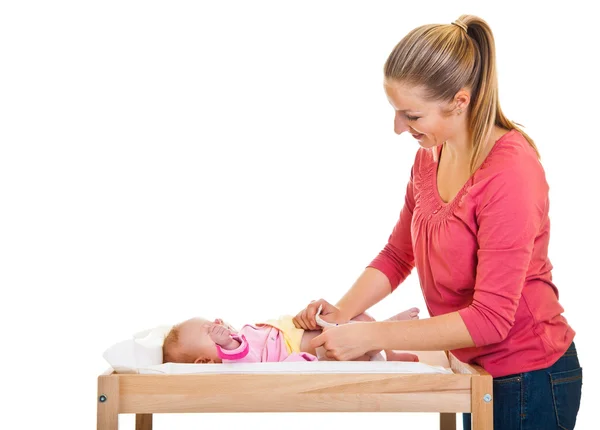 Madre cambiando pañal de niña en la mesa del vivero —  Fotos de Stock