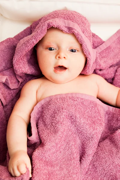 Infant baby girl smiling laying in violet towel — Stock Photo, Image