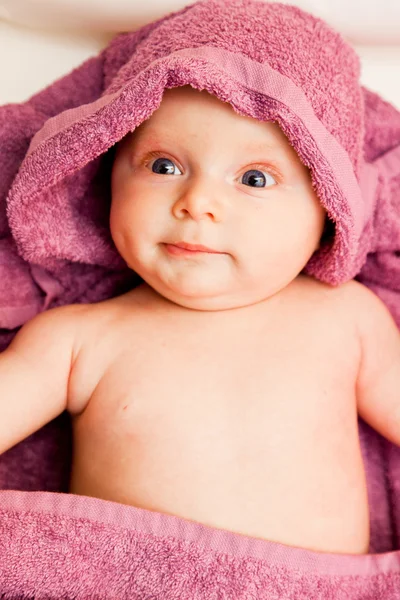 Infant baby girl smiling laying in violet towel — Stok fotoğraf
