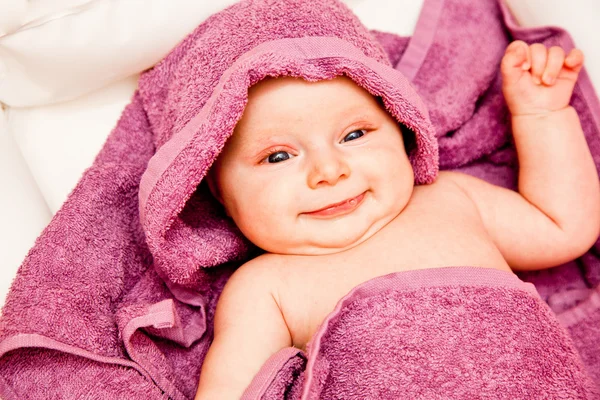 Csecsemő baba lány mosolyogva, lila törülközőt megállapításáról — Stock Fotó