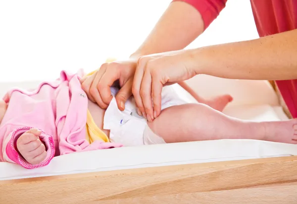 Mother changing little girl's diaper on nursery table — Stock Photo, Image