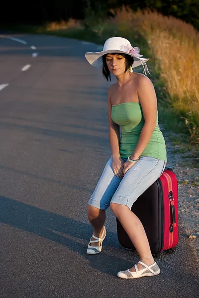 Kvinna som sitter på en resväska — Stockfoto