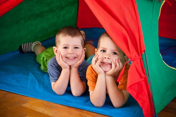 Niños pequeños acostados dentro de carpa colorida — Foto de Stock