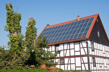 Old frame house with solar cells on the roof clipart