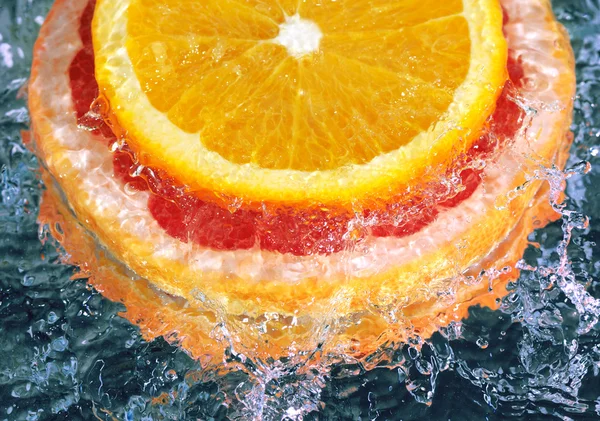Апельсин и грейпфрут в потоковой воде — стоковое фото