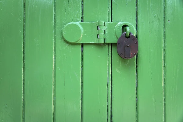 Lucchetto arrugginito porta di legno verde — Foto Stock