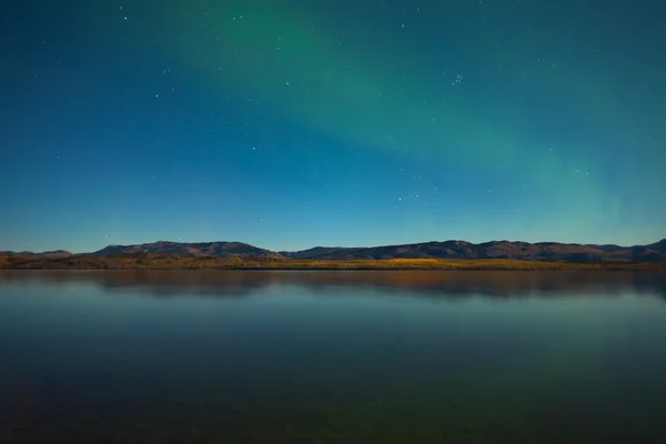 Северное сияние и осенние цвета на спокойном озере — стоковое фото
