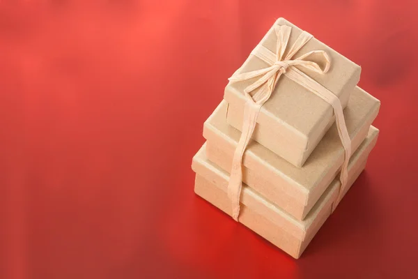 Três caixas de papelão presentes no fundo vermelho — Fotografia de Stock