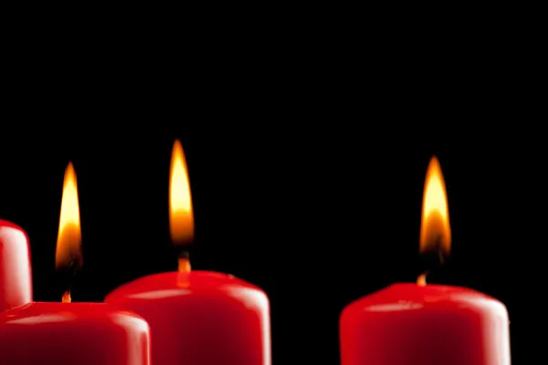 Quatro velas vermelhas sobre preto — Fotografia de Stock