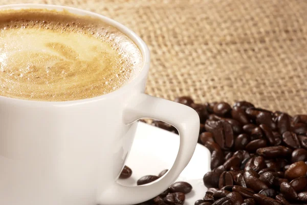 Cappuccino dan biji kopi di atas karung — Stok Foto