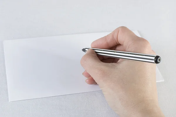 Main féminine tenant un stylo et écrivant sur une enveloppe blanche — Photo