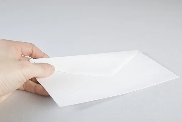 Mão feminina segurando um envelope sobre fundo branco . — Fotografia de Stock