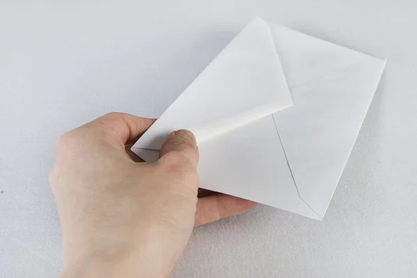 Mão feminina segurando um envelope sobre fundo branco . — Fotografia de Stock