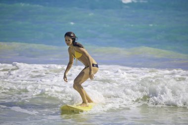 Brunette in bikini surfing clipart