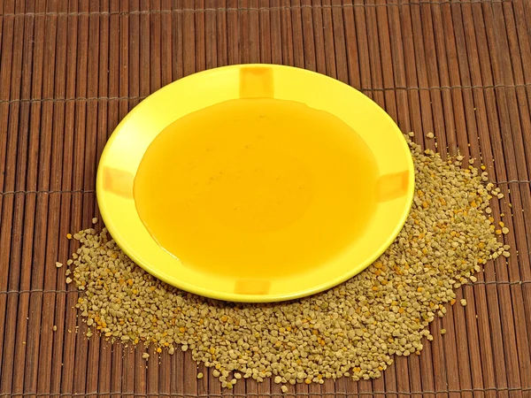 Honey in yellow plate and flower pollen. — Stock Photo, Image