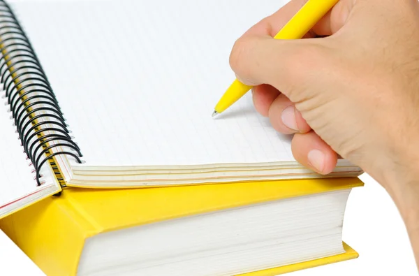 Nahaufnahme von Hand mit Stift auf einem gelben Textbuch. lizenzfreie Stockfotos