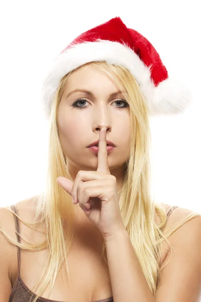 Schöne blonde Frau mit Weihnachtsmannmütze, die Finger auf den Mund legt, um — Stockfoto