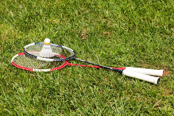 Two badminton rackets and shuttlecock on the grass — Zdjęcie stockowe